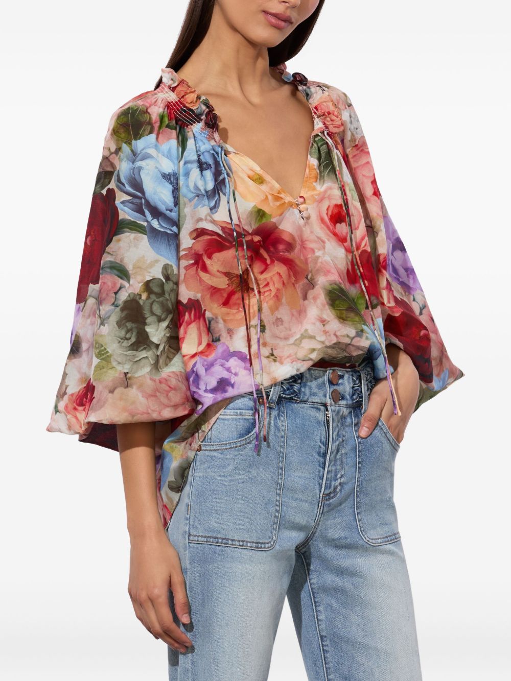 Woman wearing a colorful floral blouse and jeans on a white background